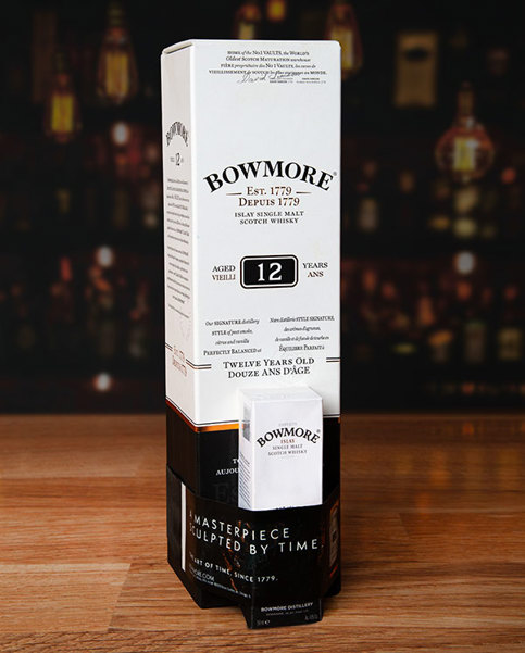 Bowmore 12 Year Old Islay Single Malt Scotch Whisky box with a smaller box attached with elastomer band. Bottles partially visible behind.