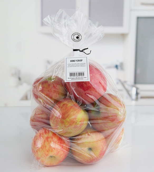 Bag of Honeycrisp apples from Nystrom Orchard with description, barcode, and contact info shared on a tag hanging from the bag opening by a black twist tie. 