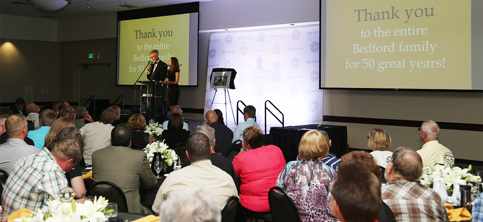 A crowd gives attention to a man and woman on a stage at a podium.