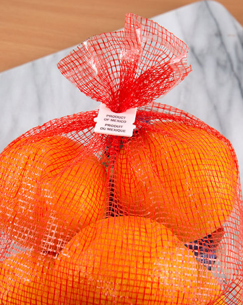 Bag of oranges with a white, tab-style bag closure with "Product of Mexico" printed on clip.