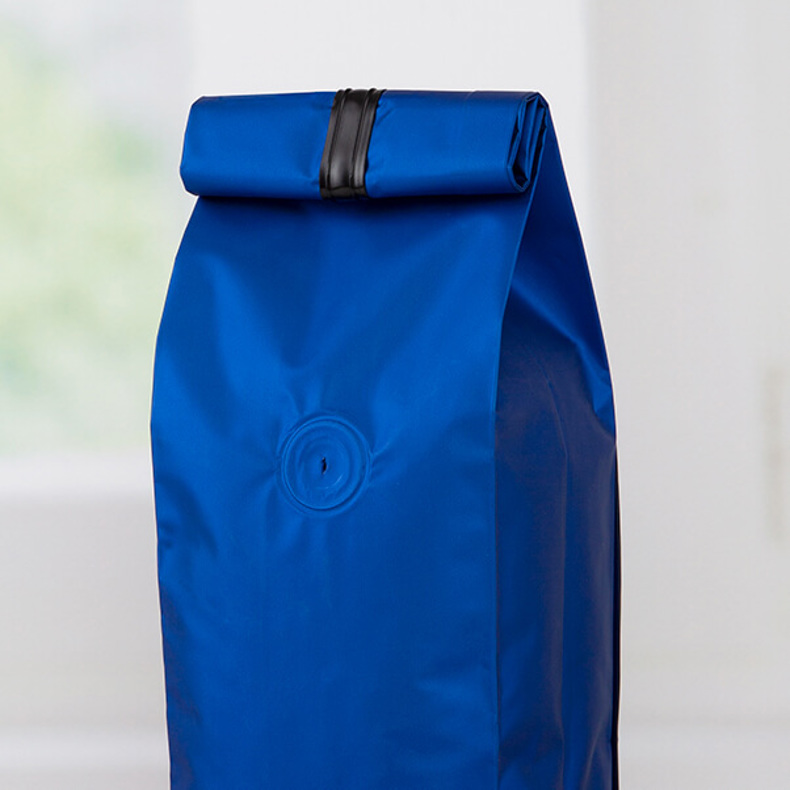 Dark blue coffee back with single black RollNClose tin tie on center bag with light kitchen background.