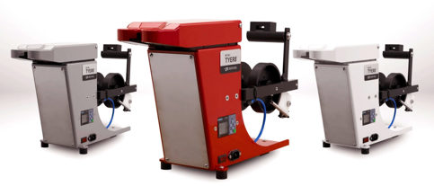 Three Bedford Mini Tyer machines, one red, one gray, one white, with spools and digital displays, on a light gray surface.
