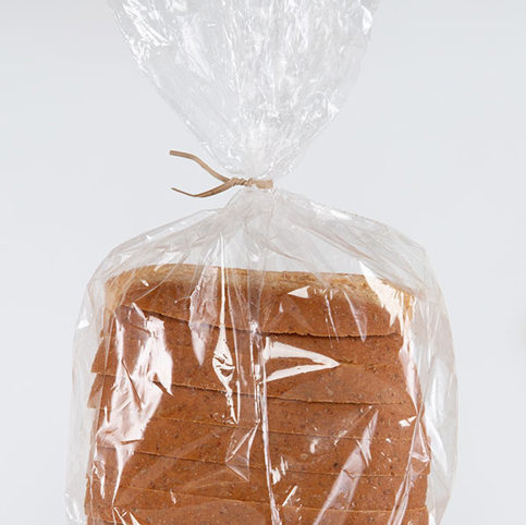 a tan, Kraft paper recycled twist tie closing a loaf of white bread. 