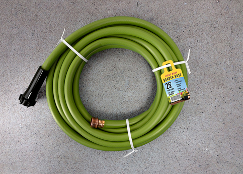 A green garden hose coiled up with twist tie and a Ring Tag attached noting the hose as "Heavy Duty" and 25 feet long.