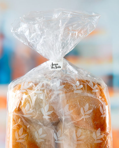 A white clip bag closure with "Juana de Avila" in black script font on a bag of bread buns.