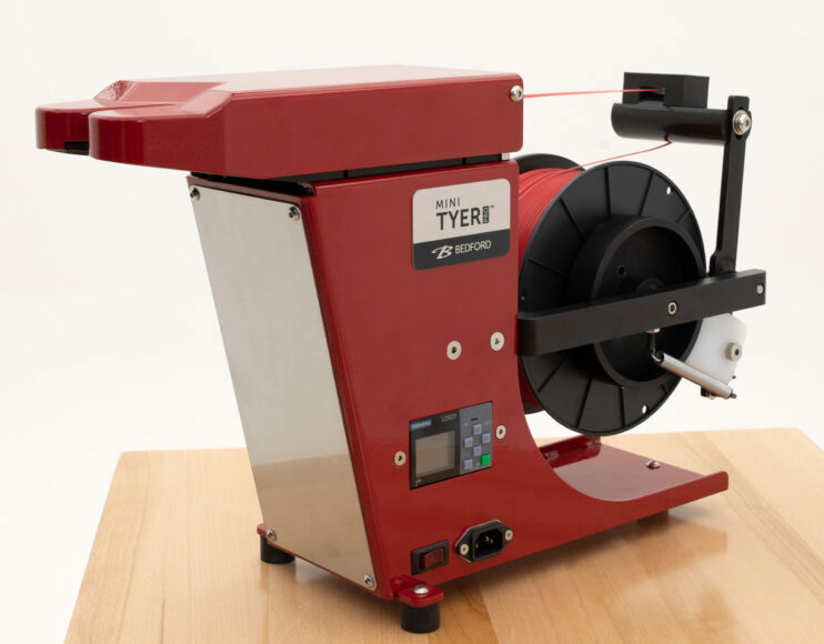 A red tabletop twist tie machine.