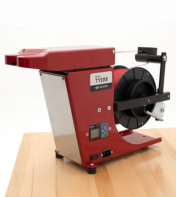 A red twist tie machine with spool of red twist tie.