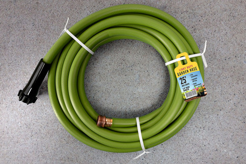 A green garden hose coiled up with twist tie and a Ring Tag attached noting the hose as "Heavy Duty" and 25 feet long.