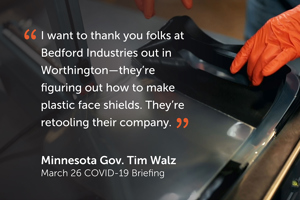 Orange-gloved hands grab a stack of face shields in background of quote ""I want to thank you folks at Bedford Industries out in Worthington – they're figuring out how to make plastic face shields. They're retooling their company." - Minnesota Gov. Tim Walz, March 26 Covid-18 Briefing."