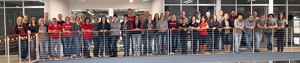 A large group of people with Bedford shirts on in front of a long railing.