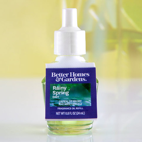 Better Homes & Gardens Rainy Spring Day fragrance oil refill bottle. White cap, blue elastic tag label, on a light surface.