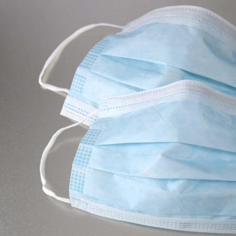 Two light blue face masks with flexible wire nosepiece against grey background.