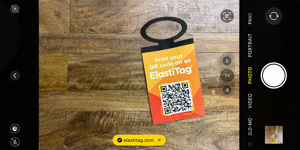 A phone taking a picture and scanning a QR code on an ElastiTag hangtag.