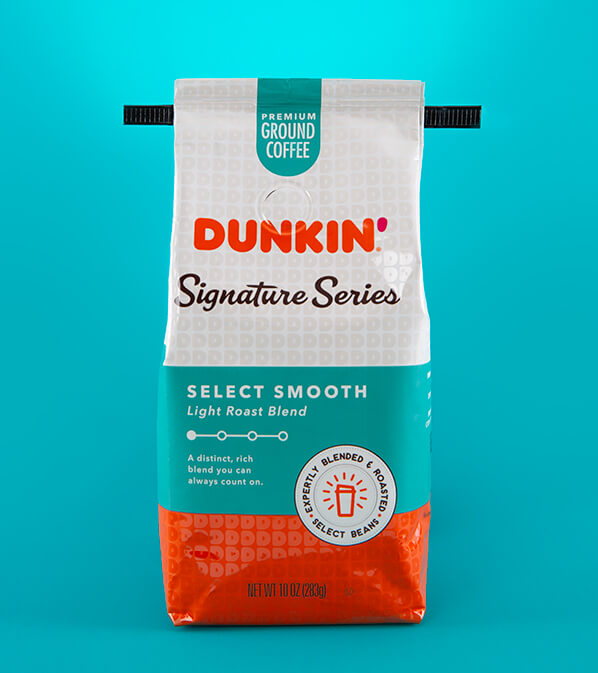 Dunkin' Donuts Signature Series coffee bag with black tin tie ears extended against teal background.