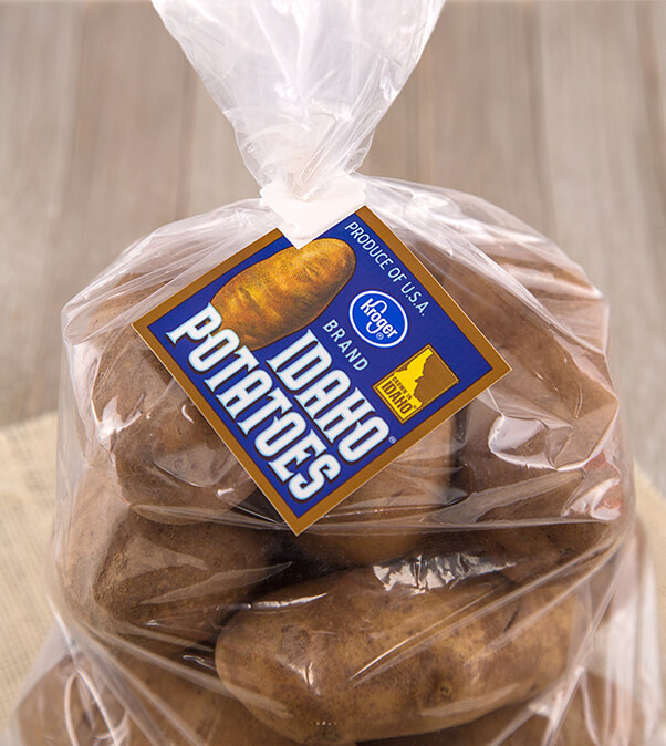 Bag of potatoes with brown background secured by white bag clip with blue flag that says Kroger brand Idaho potatoes.