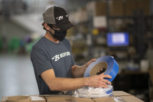 A man inspects a roll of blue Double Wire Tin Tie.