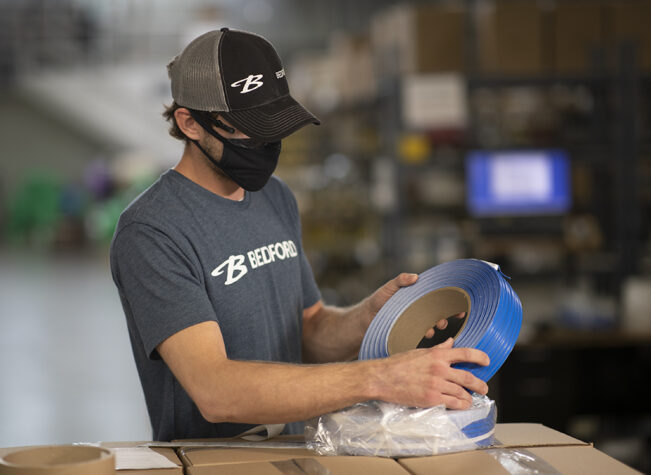 A man inspects a roll of blue Double Wire Tin Tie.