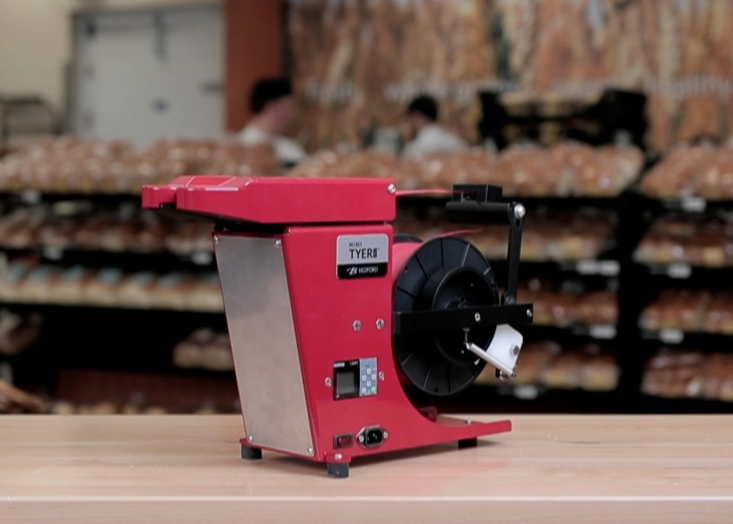 A red twist tie machine in a bakery