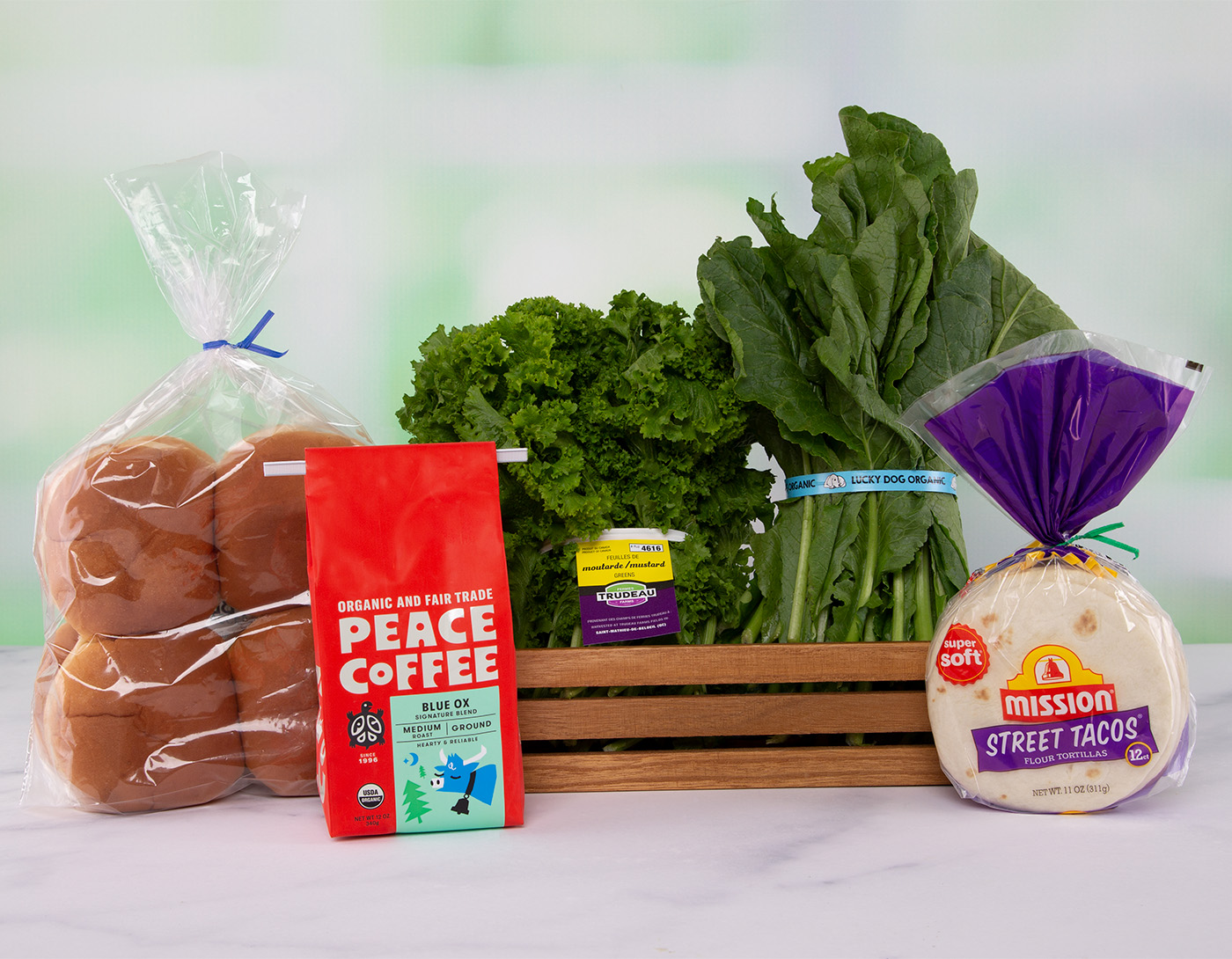 A coffee bag with tin tie, bread buns & tortilla shells with twist tie, and leafy greens with identification tags.