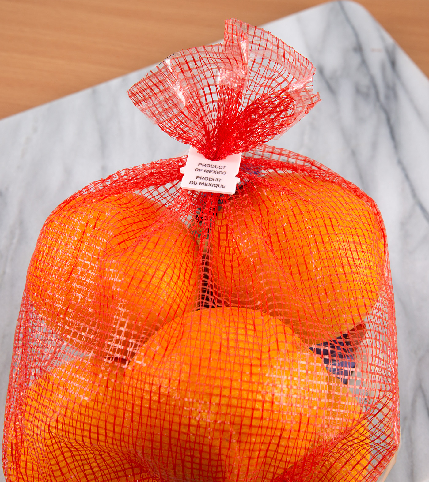 Bag of oranges with a white, tab-style bag closure with "Product of Mexico" printed on clip.