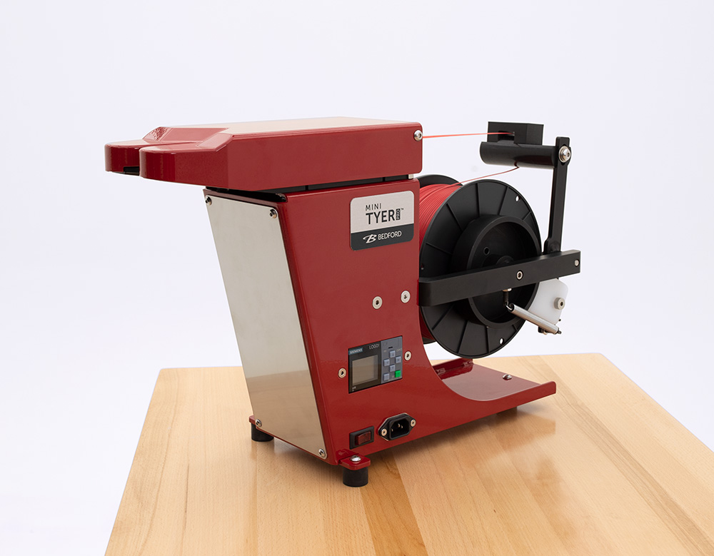 A red tabletop twist tie machine.