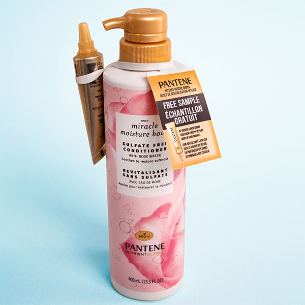 Pantene_1954 A bottle of Pantene Conditioner with a free sample bottle attached with a tote. The bottle is pink and white and has a picture of a rose on it.