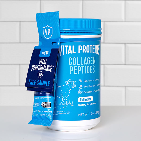 Vital Proteins_2188 A blue container of Vital Proteins Collagen Peptides with a smaller packet of a free sample attached with an ElastiTag tote. The container is on a white tiled background.